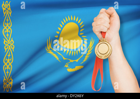 Sportler halten Goldmedaille mit Flagge auf Hintergrund - Kasachstan Stockfoto