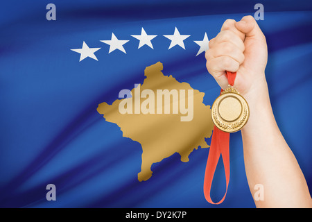 Sportler halten Goldmedaille mit Flagge auf Hintergrund - Kosovo Stockfoto