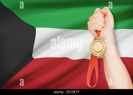 Sportler halten Goldmedaille mit Flagge auf Hintergrund - Staat Kuwait Stockfoto