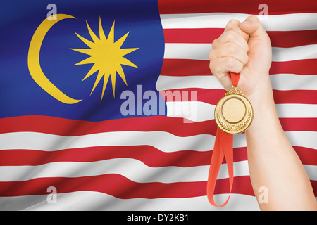 Sportler halten Goldmedaille mit Flagge auf Hintergrund - Malaysia Stockfoto