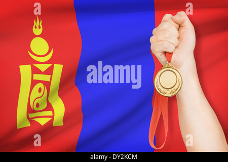 Sportler halten Goldmedaille mit Flagge auf Hintergrund - Mongolei Stockfoto