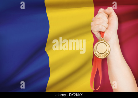 Sportler halten Goldmedaille mit Flagge auf Hintergrund - Rumänien Stockfoto