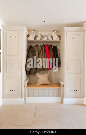 Eine Sitzbank zwischen zwei hölzerne Lagerung Schränke. Coats Hangfrom Stifte oben Stockfoto