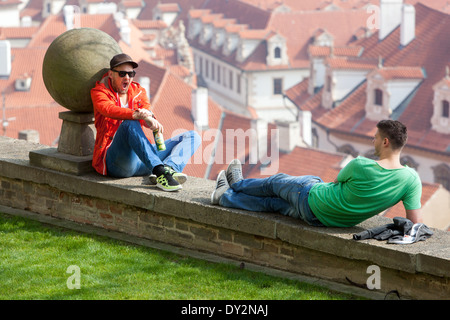 Zwei junge Männer sitzen an der Wand. Blick von der Prager Burg auf Mala Strana, Prag, Tschechische Republik Stockfoto