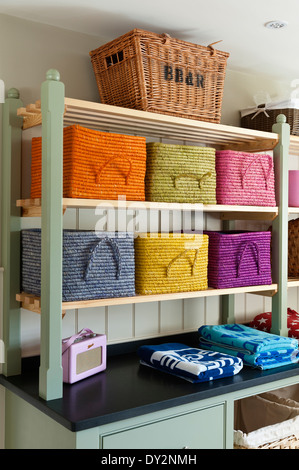 Bunte Körbe aus Burford Gartencenter im Hauswirtschaftsraum mit hölzernen Regalen und gefaltete Handtücher Stockfoto