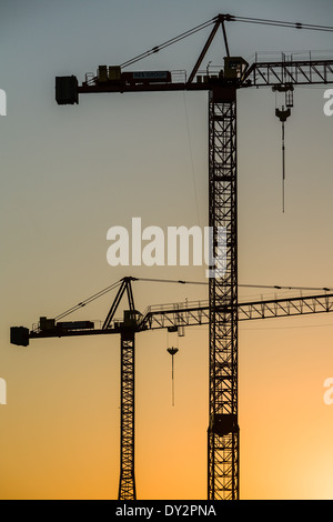 Zwei Baukräne mit Sonnenuntergang Hintergrund. Stockfoto