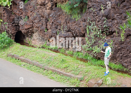 Touristen fotografieren Menehune Grabenmauer, ein altes Bewässerungssystem aus Basaltsteinblöcken in Waimea, Kauai, Hawaii Stockfoto