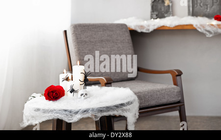 Graue Polsterstuhl in Halloween Ambiente mit Kerzen Stockfoto