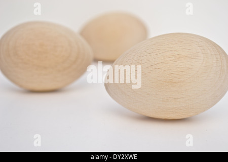 Drei Holz Eiern von vorne nach hinten auf der einen Seite des Fotos angeordnet. Die hölzernen Eiern sind in natürlichem Licht und Farbe. Stockfoto