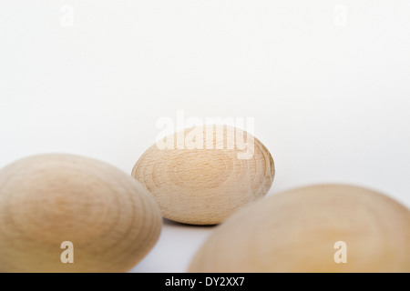 Drei Holz Eiern von vorne nach hinten auf der einen Seite des Fotos angeordnet. Die hölzernen Eiern sind in natürlichem Licht und Farbe. Stockfoto