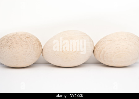 Drei Holz Eiern von vorne nach hinten auf der einen Seite des Fotos angeordnet. Die hölzernen Eiern sind in natürlichem Licht und Farbe. Stockfoto