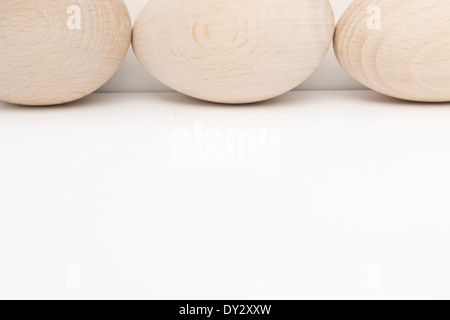 Drei Holz Eiern von vorne nach hinten auf der einen Seite des Fotos angeordnet. Die hölzernen Eiern sind in natürlichem Licht und Farbe. Stockfoto