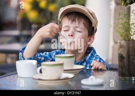 Niedlichen kleinen Jungen trinken Milchshake im Restaurant unter freiem Himmel Stockfoto