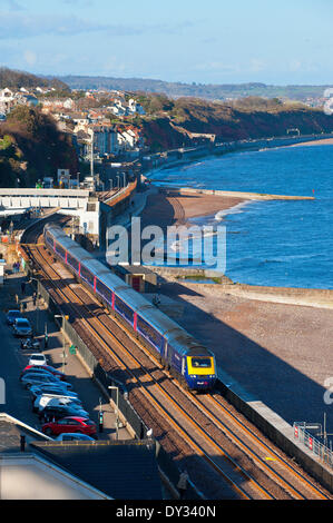 Dawlish, Devon, UK. 4. April 2014. Das Meer ist ruhig, da ein Zug die Station für Plymouth fährt. Die Riviera Linie Eisenbahnverbindung Exeter, öffnet Plymouth und Penzance zwei Wochen früher als geplant und zwei Monate nach einer Ufermauer verletzt wurde und eine Strecke der Linie wurde schwer beschädigt in Dawlish am 4. Februar 2014 durch große Wellen und Stürme, die viel von der britischen Küste am 4. Februar 2014 getroffen. Bildnachweis: Graham M. Lawrence/Alamy Live-Nachrichten. Stockfoto