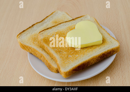 zwei Scheiben Toast auf einem weißen Teller mit herzförmigen butter Stockfoto