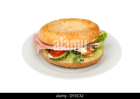 Salat mit Schinken in einem Bagel Sesam ausgesät auf einem Teller isoliert gegen weiß Stockfoto