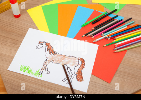 von einem Kind gemalt Pony auf einem weißen Papier, liegen auf einem Tisch mit Bleistiften und bunten Karton Stockfoto