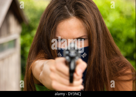 Seriuos sucht Frau in Gesichtsmaske richtet Waffe auf Sie Stockfoto