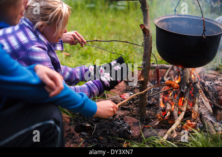 Zubereitung von Speisen in Wildnis, Backen Wurst am Kamin Stockfoto