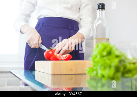 Frau macht einen Salat mit Olivenöl, Tomaten und Salat Stockfoto