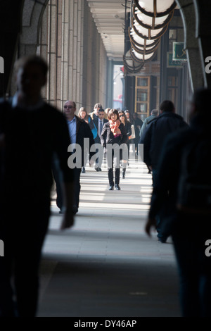 Fußgänger, die in Broadgate in der Nähe der Liverpool Street Station, Central London, Großbritannien, während der Hauptverkehrszeit am Morgen durch einen Durchgang laufen. Geschäftige Pendlerszene im Herzen des Finanzviertels. Stockfoto