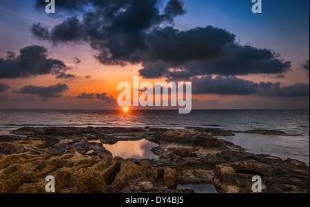 Bewölkten Sonnenuntergang über dem Meer und Felsstrand Stockfoto