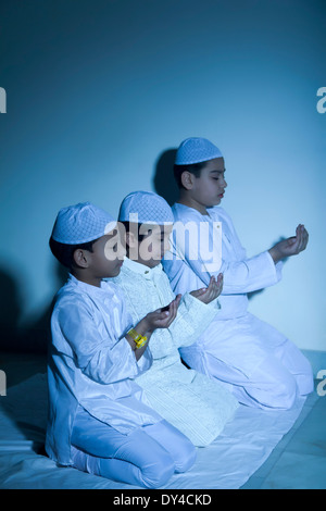 Indische muslimische Kinder sitzen und Prayering Stockfoto