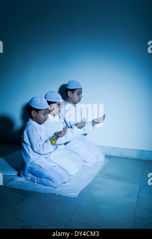 Indische muslimische Kinder sitzen und Prayering Stockfoto