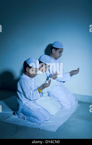 Indische muslimische Kinder sitzen und Prayering Stockfoto