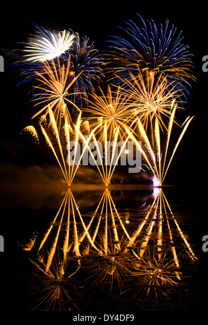 Goldenen und blauen Feuerwerk reflektiert in einem trüben See Stockfoto