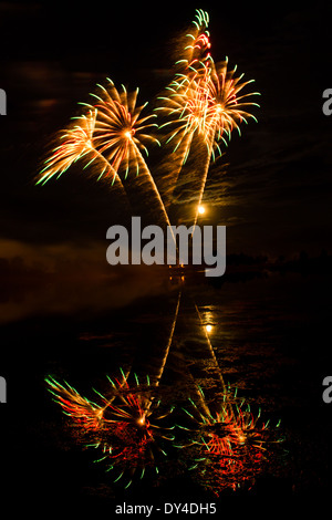 Rot, grün und Gold Feuerwerk im trüben See widerspiegelt Stockfoto