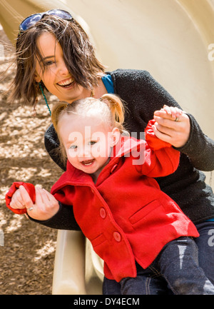 Schöne junge Mutter mit 16 Monate Baby Girl auf Park Spielplatz spielen Stockfoto