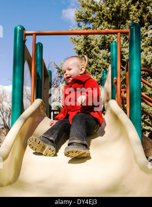 Liebenswert, niedlich 16 Monat kleine Mädchen spielen auf einem Park Schiebe-Board Stockfoto