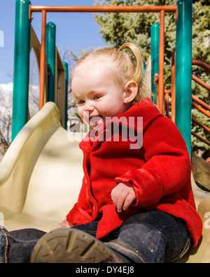 Liebenswert, niedlich 16 Monat kleine Mädchen spielen auf einem Park Schiebe-Board Stockfoto