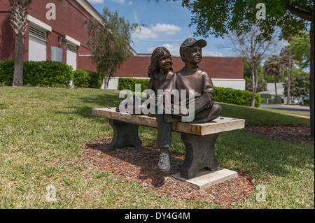 Bronzestatue von Kindern ein Buch auf einer Bank außerhalb der Leesburg, Florida-Bibliothek Stockfoto