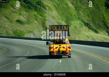 Straßenbau weiter befolgen Sie den pilot LKW auf einer Straße durch die Berge. Leuchtreklame sagt folgen mir. Stockfoto