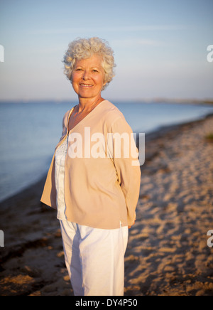 Porträt der älteren Frau, die allein am Strand. Senior kaukasischen Dame entspannen im freien Stockfoto