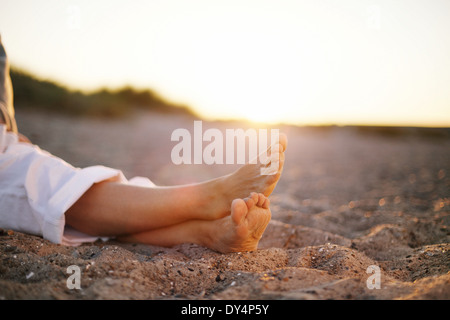 Nahaufnahme Bild der Beine des senior Frau sitzt entspannt am Sandstrand. Stockfoto