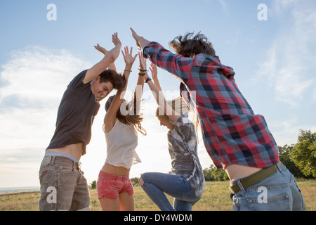 Vier Freunde springen mit erhobenen Armen Stockfoto
