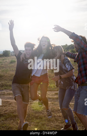 Vier Freunde springen mit erhobenen Armen Stockfoto