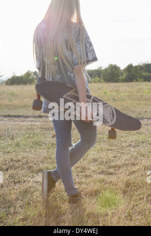 Junge Frau Holding skateboard Stockfoto