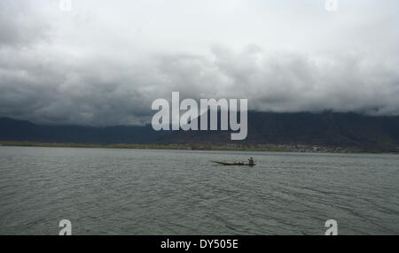 Srinagar, indische verabreicht Kaschmir. 7. April 2014. Ein Kashmiri Mann reitet sein Boot während bewölkten Himmel bei weltweit berühmten Dal-See in Srinagar Credit: Sofi Suhail/Alamy Live News Stockfoto