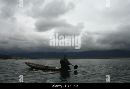 Srinagar, indische verabreicht Kaschmir. 7. April 2014. Ein Kashmiri Mann reitet sein Boot während bewölkten Himmel bei weltweit berühmten Dal-See in Srinagar Credit: Sofi Suhail/Alamy Live News Stockfoto