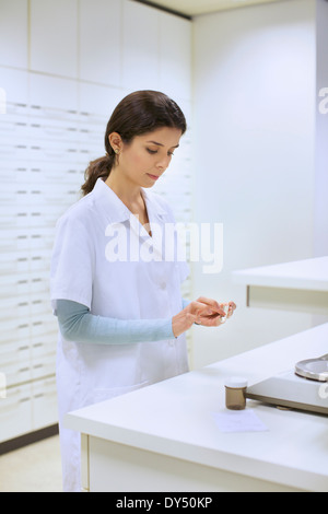 Junge Apothekerin mit einem Gewicht von Medikamenten in der Apotheke Stockfoto