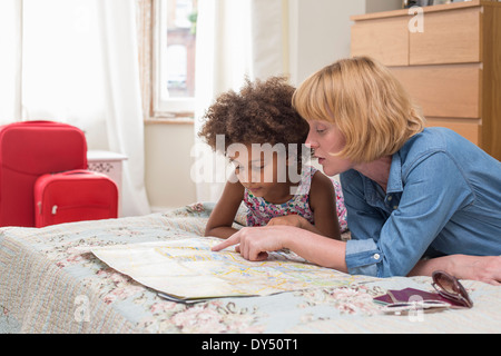 Mutter und Tochter auf Bett, Blick auf Karte Stockfoto