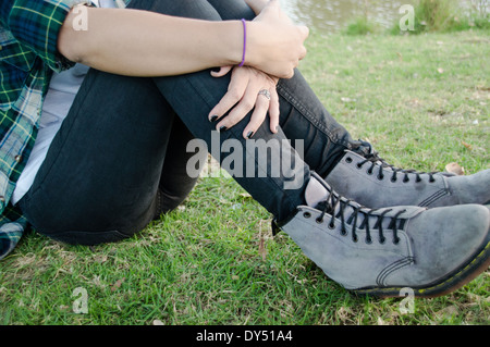 Taille abwärts, junge Frau sitzt auf dem Rasen Stockfoto