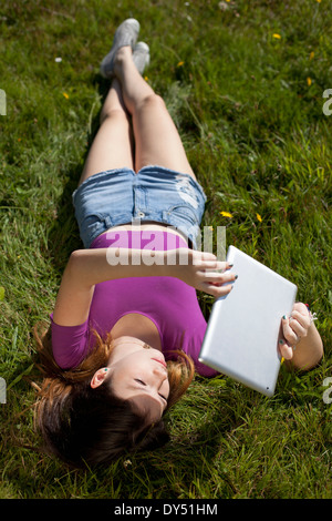 Teenager-Mädchen entspannen im Park Blick auf digital-Tablette Stockfoto