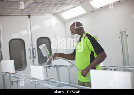 Junger Mann Spritzen Holzprodukte in Tischler Werkstatt Stockfoto