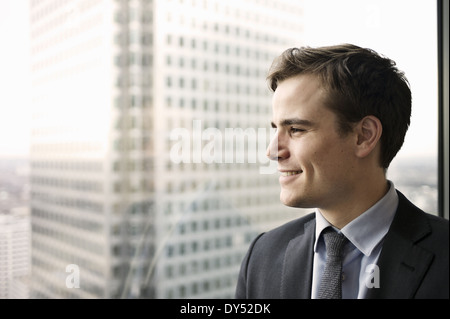 Porträt des jungen Geschäftsmann, der Blick aus dem Bürofenster Stockfoto