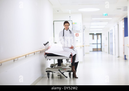Porträt der Ärztin sitzen auf Krankenhaus-Wagen im Flur Stockfoto
